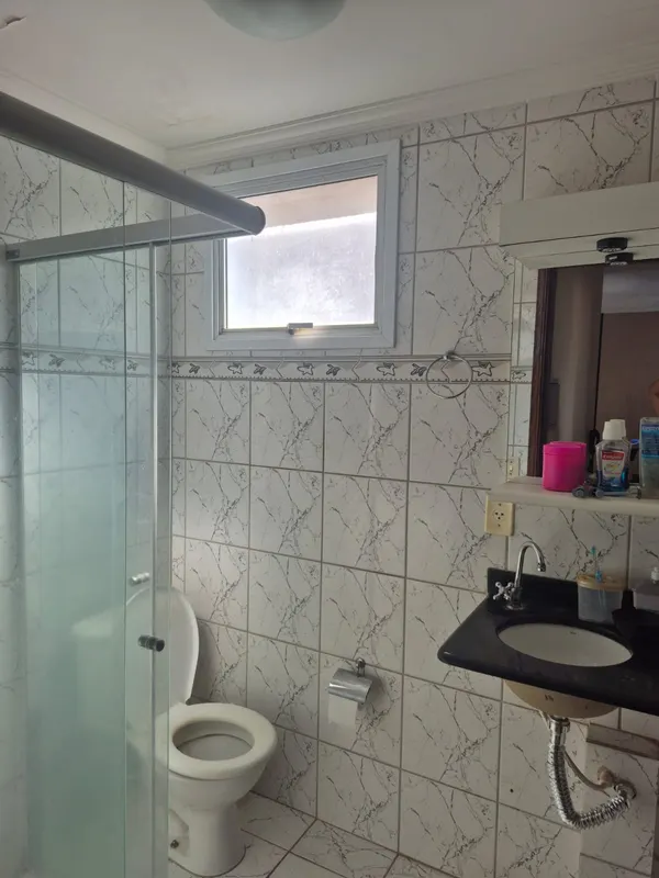 Banheiro com bancada preta, cuba branca, espelho e box de vidro