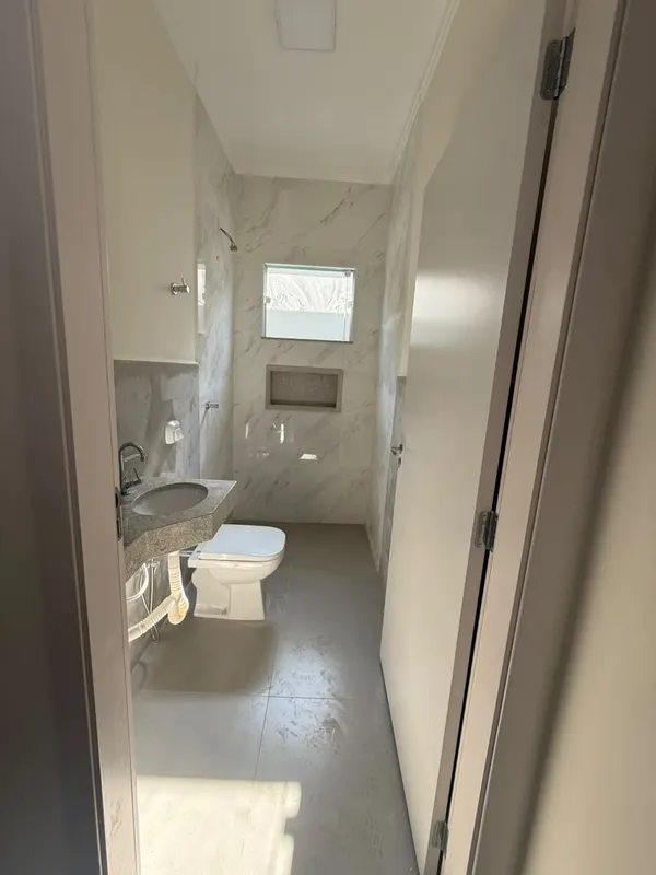 Banheiro social em porcelanato marmorizado, com nicho embutido no box
